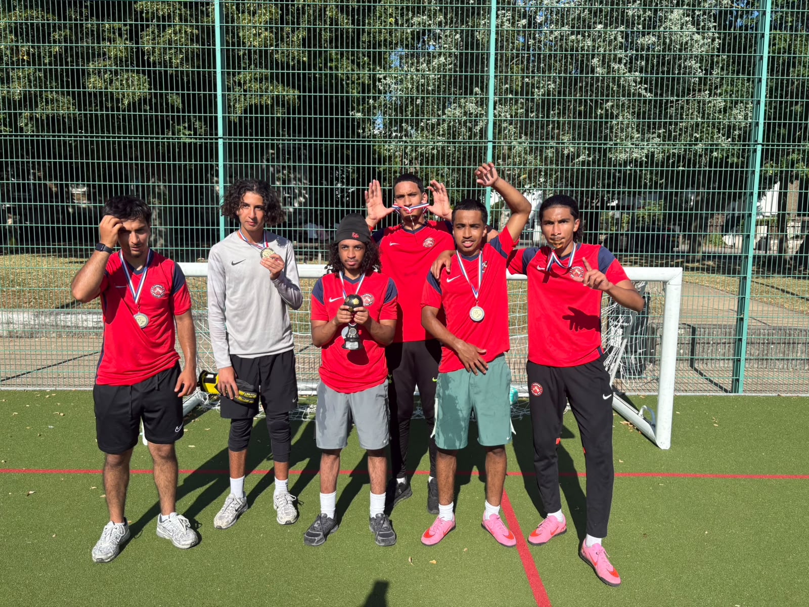 Munye League under 18 team celebrating with medals and a trophy